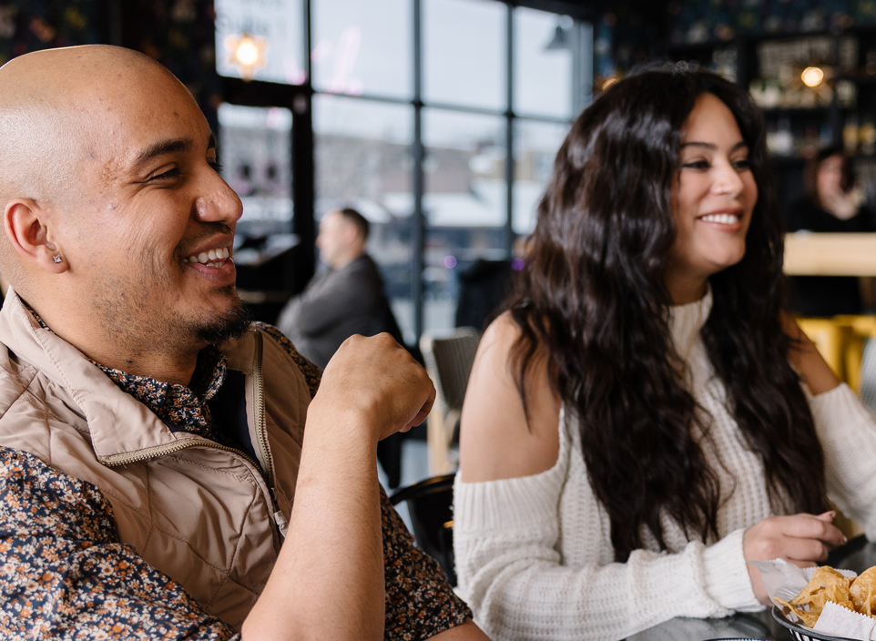 A man and a woman smile and laugh at a restaurant.